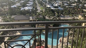 A resort with multiple swimming pools, palm trees, and a view of the surrounding residential area.