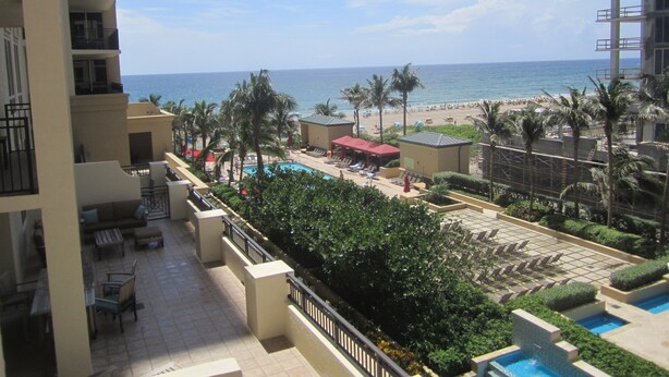 A resort with a pool, lounge chairs, and a view of the beach and ocean.