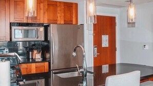 A modern kitchen with wooden cabinets, stainless steel appliances, and pendant lighting.