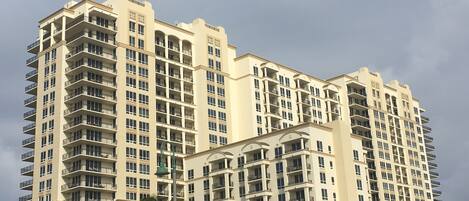 A multi-story hotel with balconies, a central courtyard, and palm trees.