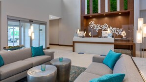 A modern lobby with a reception desk, sofas, and a decorative wall. - Wyndham Garden Miami International Airport (Miami Springs)