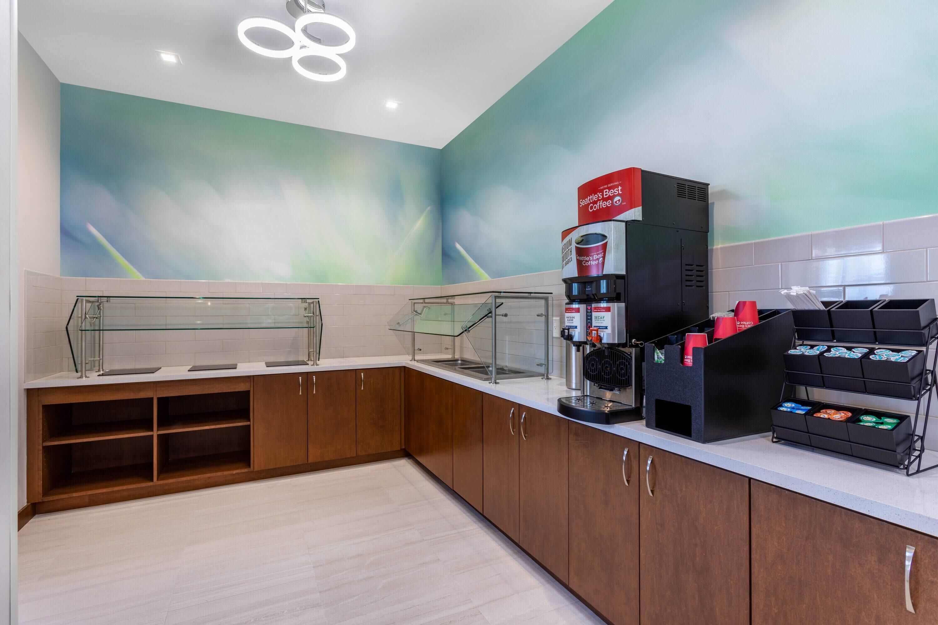 Una cocina moderna con una estación de café, una vitrina de vidrio y un mural en la pared.