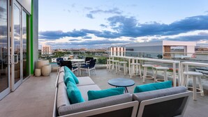 A rooftop terrace with outdoor seating, a view of the cityscape, and a glass door entrance. - Wyndham Garden Miami International Airport (Miami Springs)