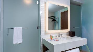 Une salle de bain moderne avec un lavabo blanc, un miroir avec éclairage intégré et un porte-serviettes.