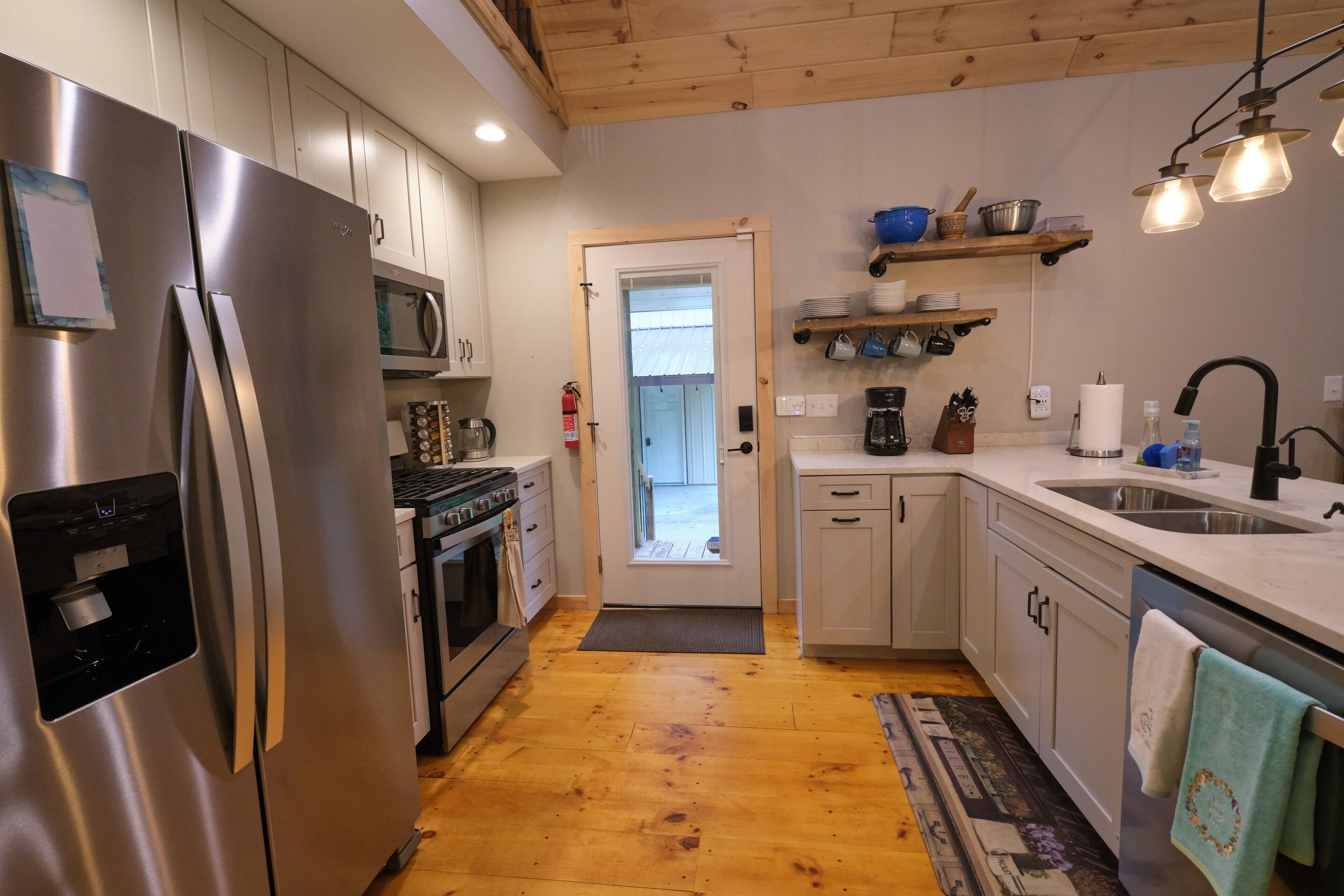 A modern kitchen with stainless steel appliances, wooden cabinets, and a view to the outside.