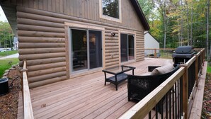 En hytte med terrasse, udendørs møbler og grill.