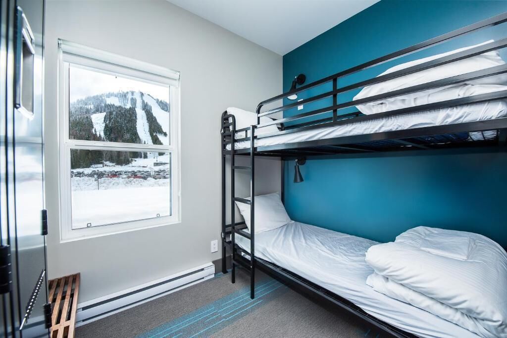 A bunk bed room with a window overlooking a snowy landscape.