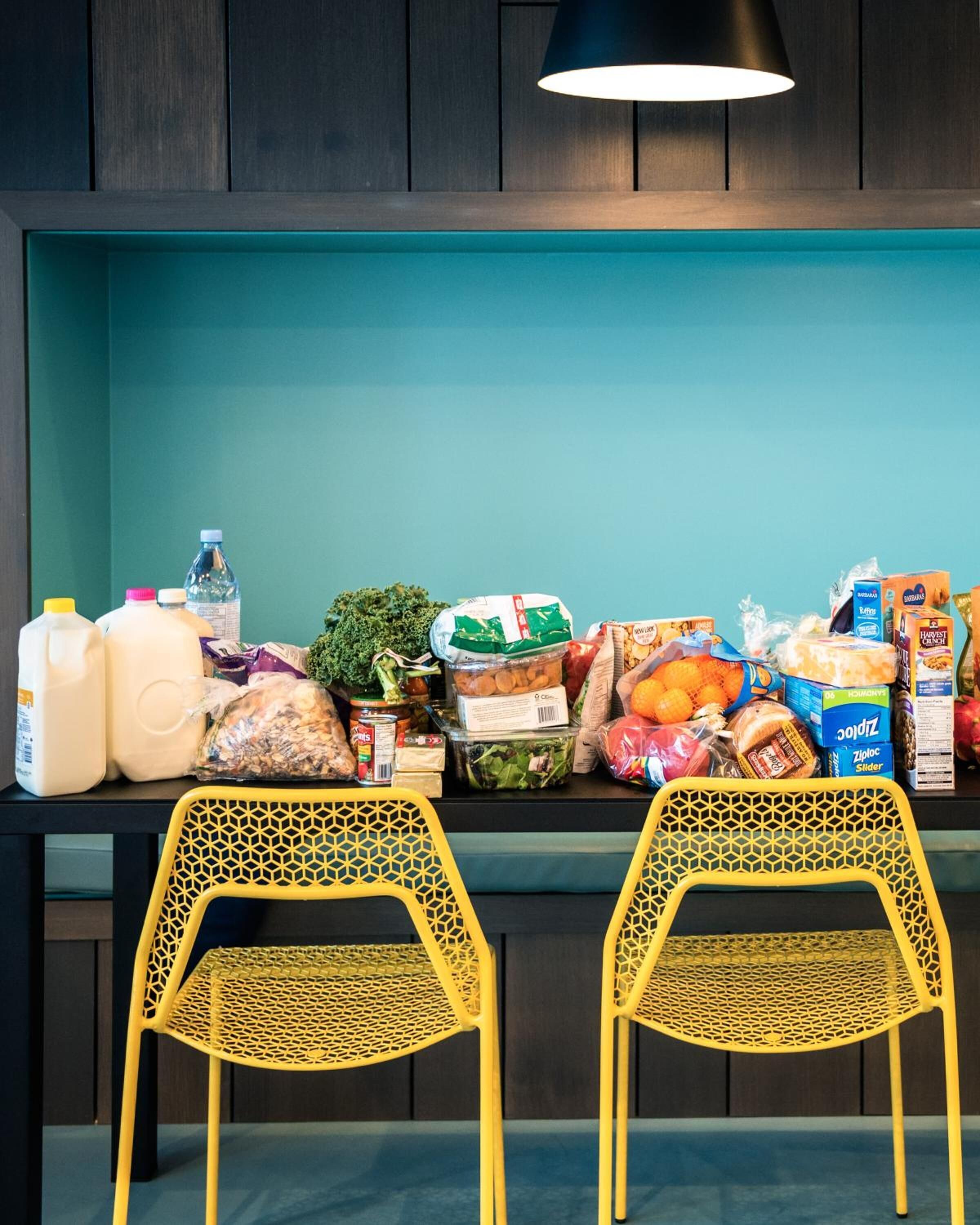 Una encimera de cocina con diversos alimentos y dos sillas amarillas.