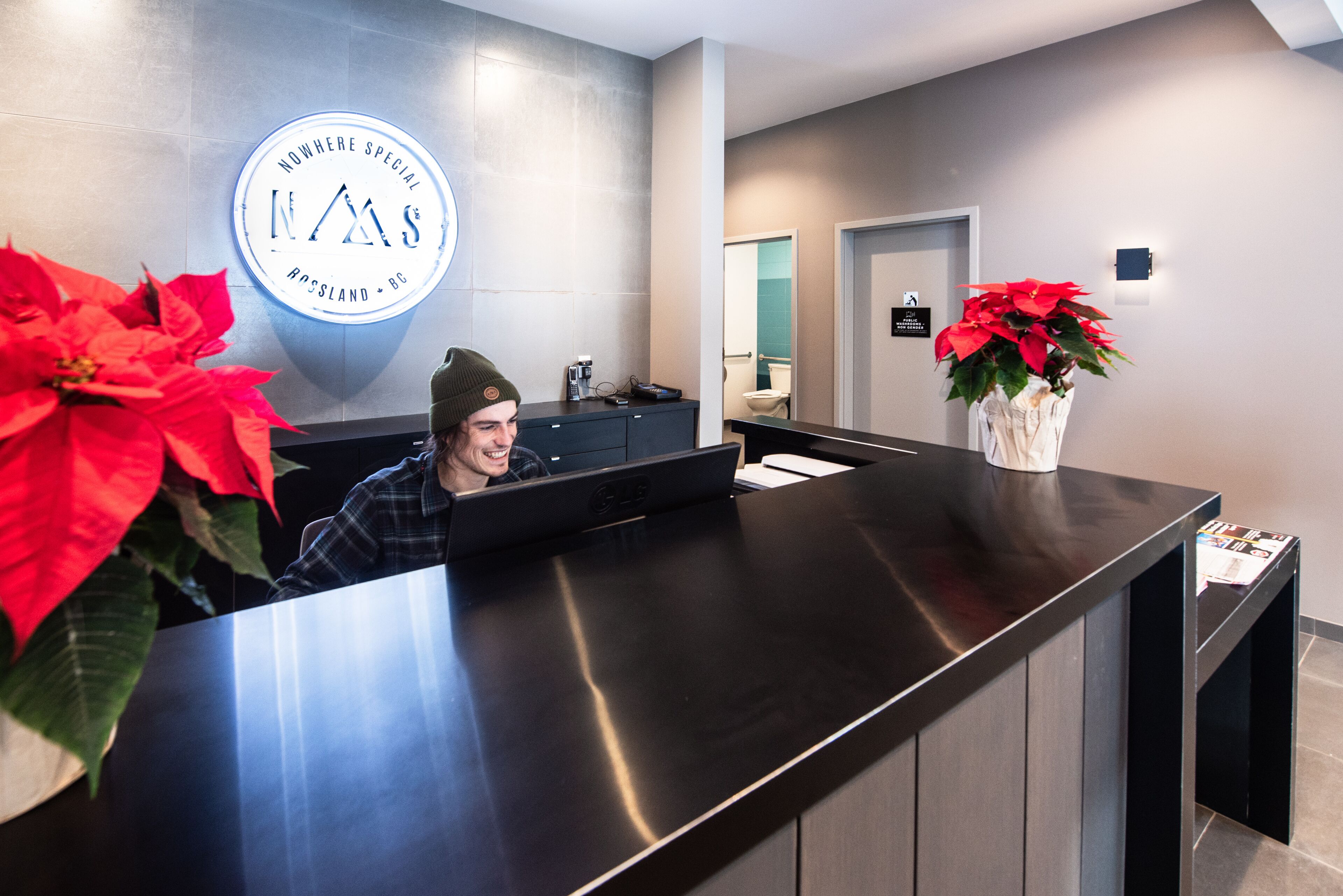 Una recepció amb un disseny modern, un logotip a la paret i una planta en test.