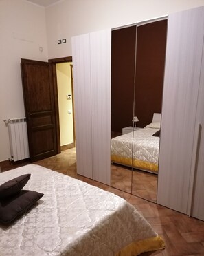 A bedroom with a bed, a wardrobe, and a mirror.