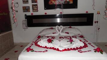 A bed with a white bedspread, red roses, and swan-shaped pillows.