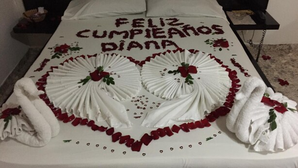 A bed with a heart-shaped towel arrangement and 'Feliz Cumpleaños Diana' written on the pillows. - Torettos (Yumbo)