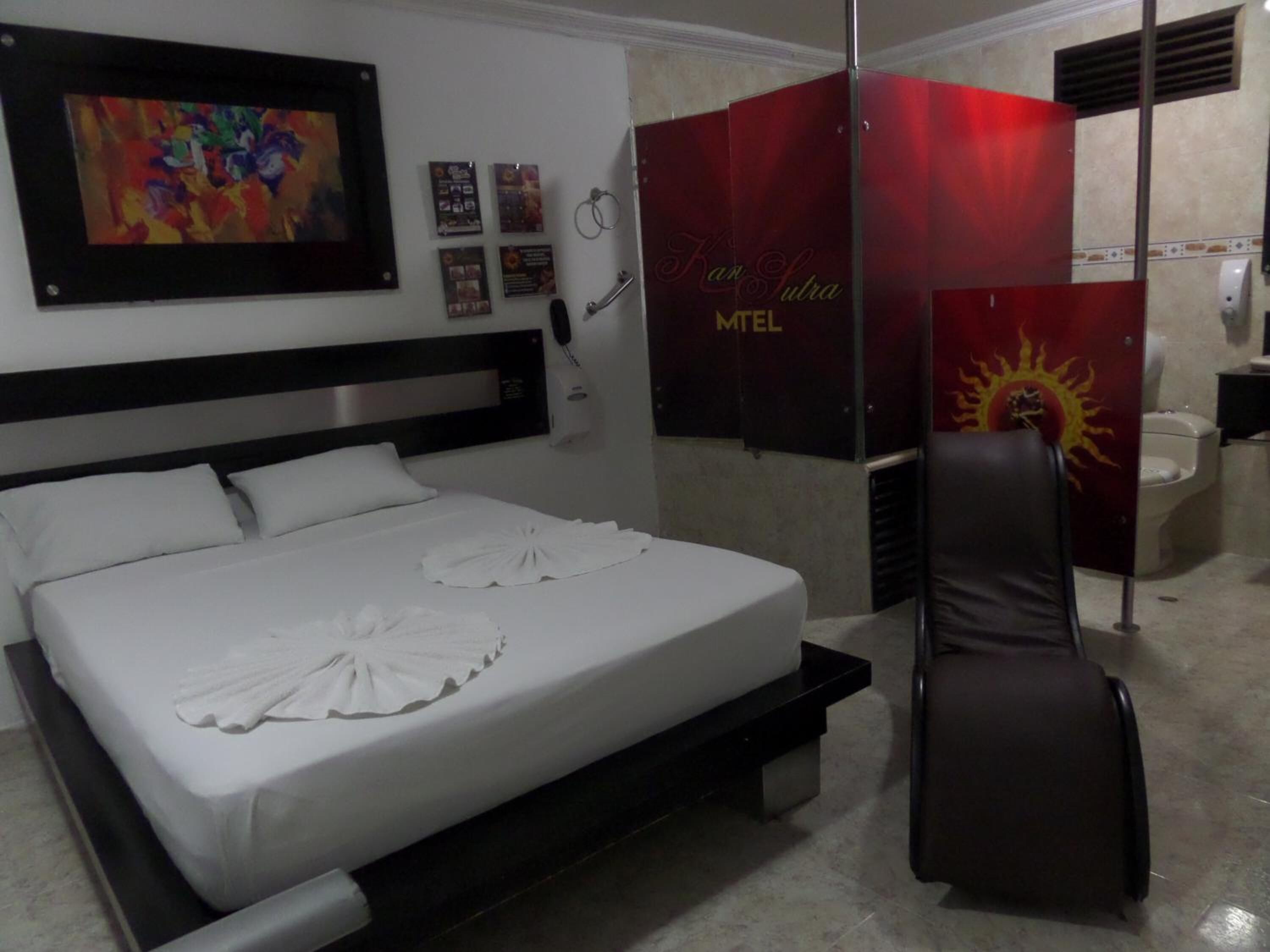 Quarto de hotel com cama, uma cadeira, casa de banho e área de duche.