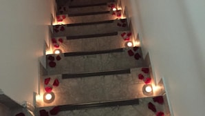 A staircase with red rose petals and candles. - Torettos (Yumbo)