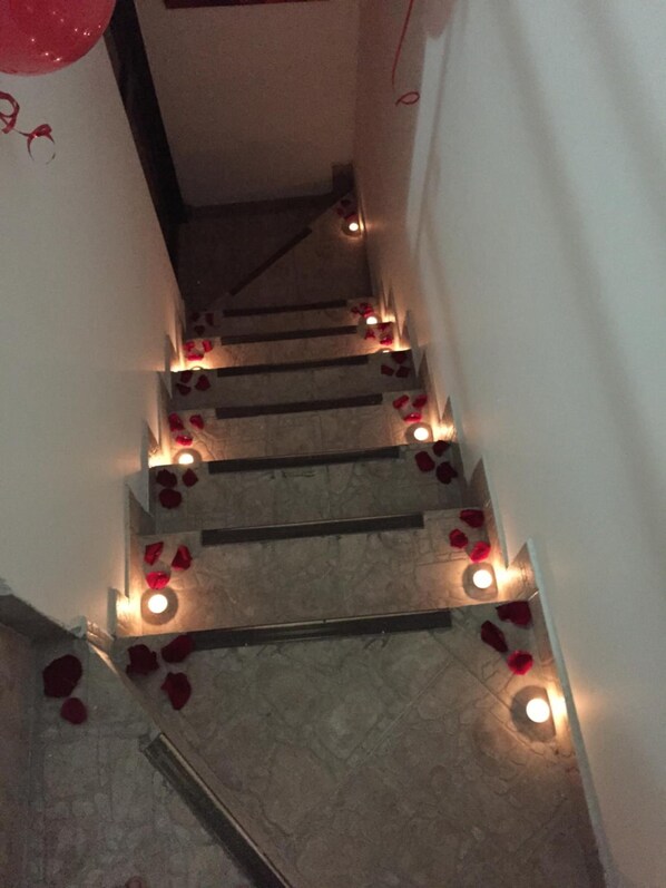A staircase with red rose petals and candles.