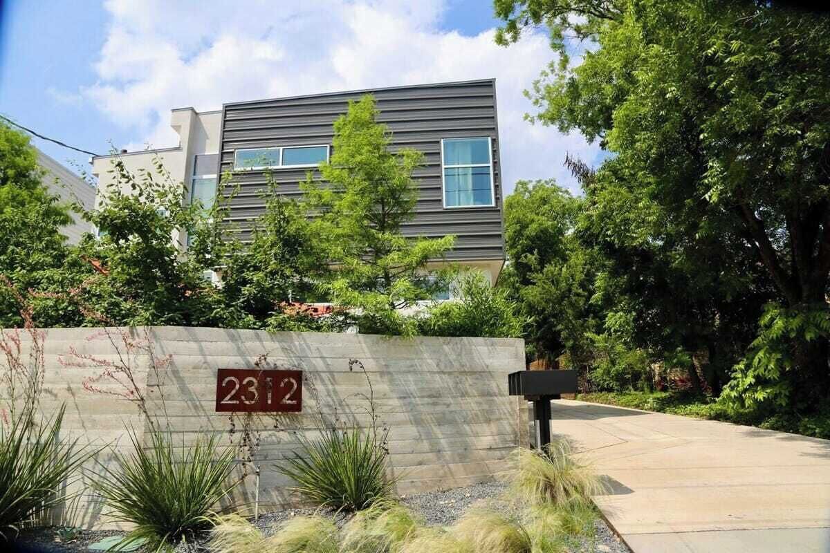 Un edificio moderno con techo plano, ventanas grandes y un cartel con el número 2312 indicando su dirección.
