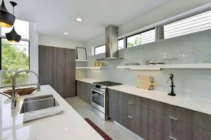 Features a stainless steel range hood, double sink, and ample counter space.
