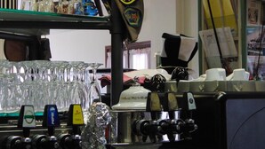 A bar area with a beer tap, glasses, and a decorative hat. - Locanda alla stazione (Mira)