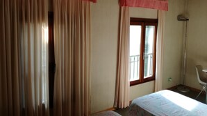 A room with a bed, a window with a view, a chair, and curtains. - Locanda alla stazione (Mira)