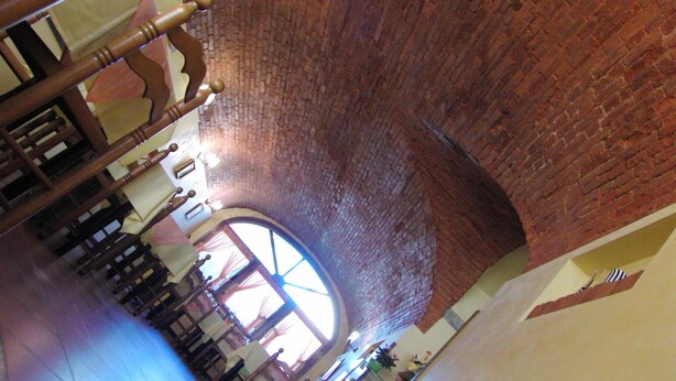 A church interior with brick walls, wooden pews, and a large circular stained glass window. - Locanda alla stazione (Mira)