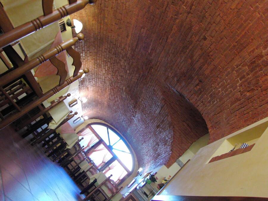 A church interior with brick walls, wooden pews, and a large circular stained glass window.