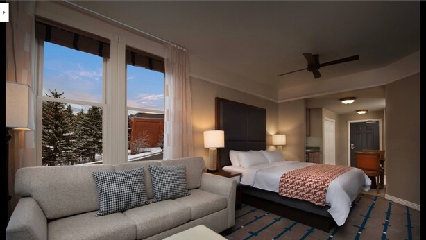 A hotel room with a bed, a sofa, a small table, and a window with a view of trees. - Marriott Summit Watch, Beautiful 1 BR, 1bath Villa, Ski in/Ski out 11/23-30/19 (Park City)