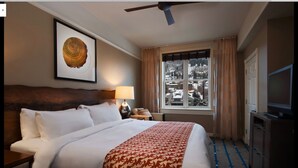 A hotel room with a bed, a headboard, a lamp, a window with curtains, a ceiling fan, and a television. - Marriott Summit Watch, Beautiful 1 BR, 1bath Villa, Ski in/Ski out 11/23-30/19 (Park City)