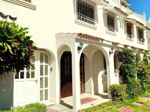 Un edificio blanco con arcos y balcones, rodeado de vegetación.
