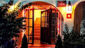 Una entrada cálidamente iluminada con un letrero que dice "Casa Blanca", una escalera que conduce al interior y plantas en macetas alrededor de la entrada.