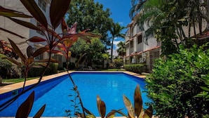 Una piscina rodeada de abundante vegetación y edificios.