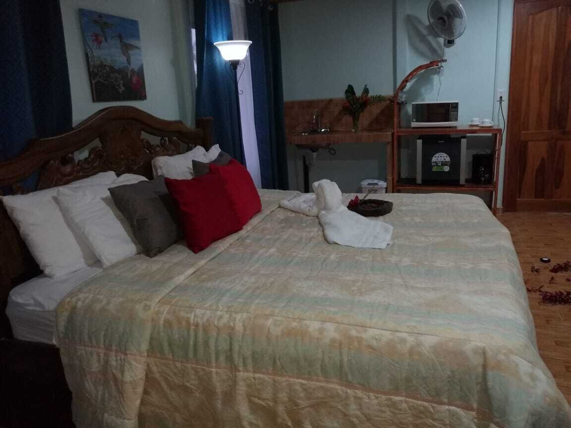 Un llit ben fet amb un estovat estampat, un coixí vermell i una tovallola blanca sobre el llit.