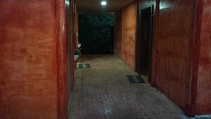 A corridor with wooden walls and a brick floor, leading to a door at the end.
