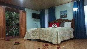 A bedroom with a wooden bed, a balcony door, and a television on the wall.
