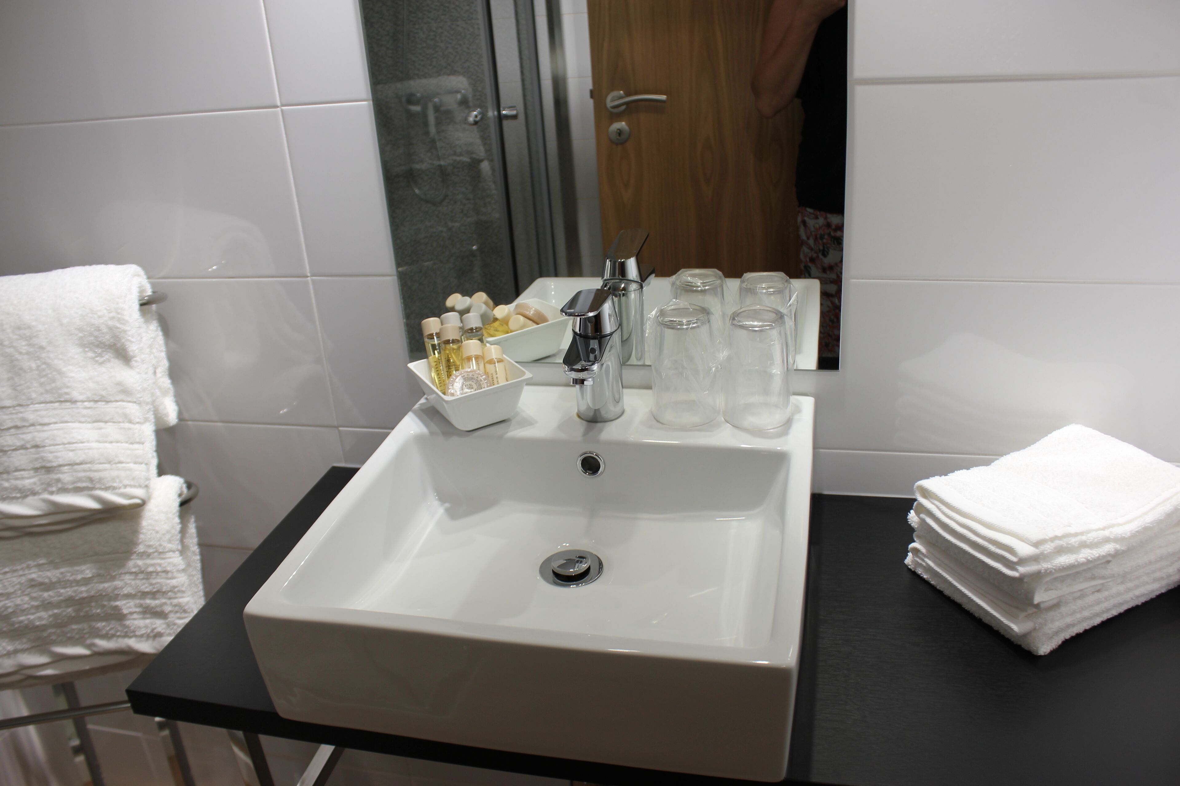 A bathroom with a white sink, a mirror, and a towel rack.