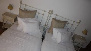 A double bed with a metal headboard, two bedside tables with lamps, and beige pillows.