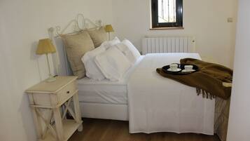 A bedroom with a bed, bedside tables, a window, and a radiator.
