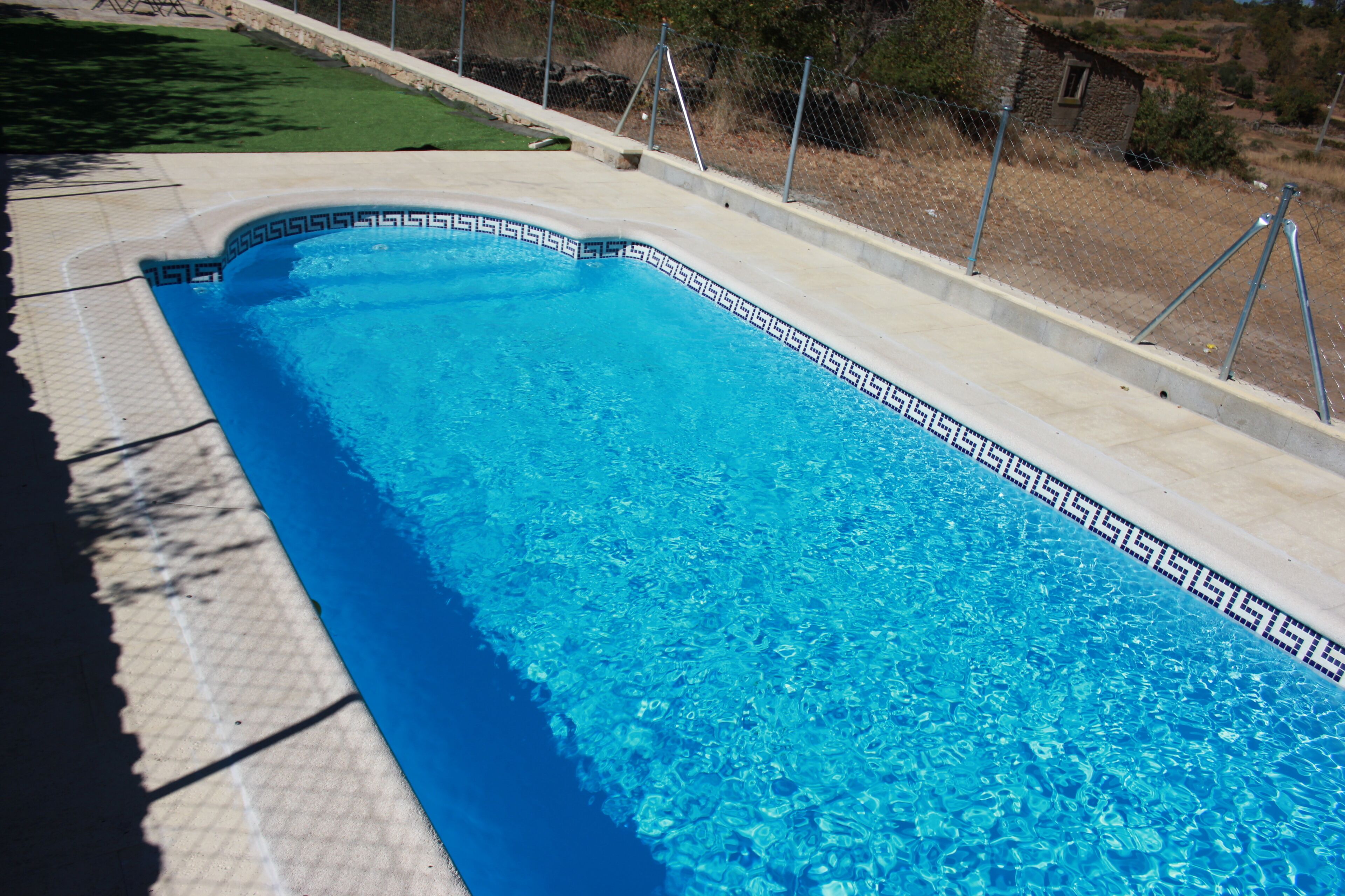Una piscina rectangular con borde de azulejos y superficie de agua azul cristalina.
