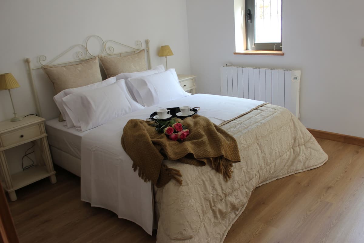 A neatly made bed with white linens, a brown throw blanket, and a tray with a cup and saucer.