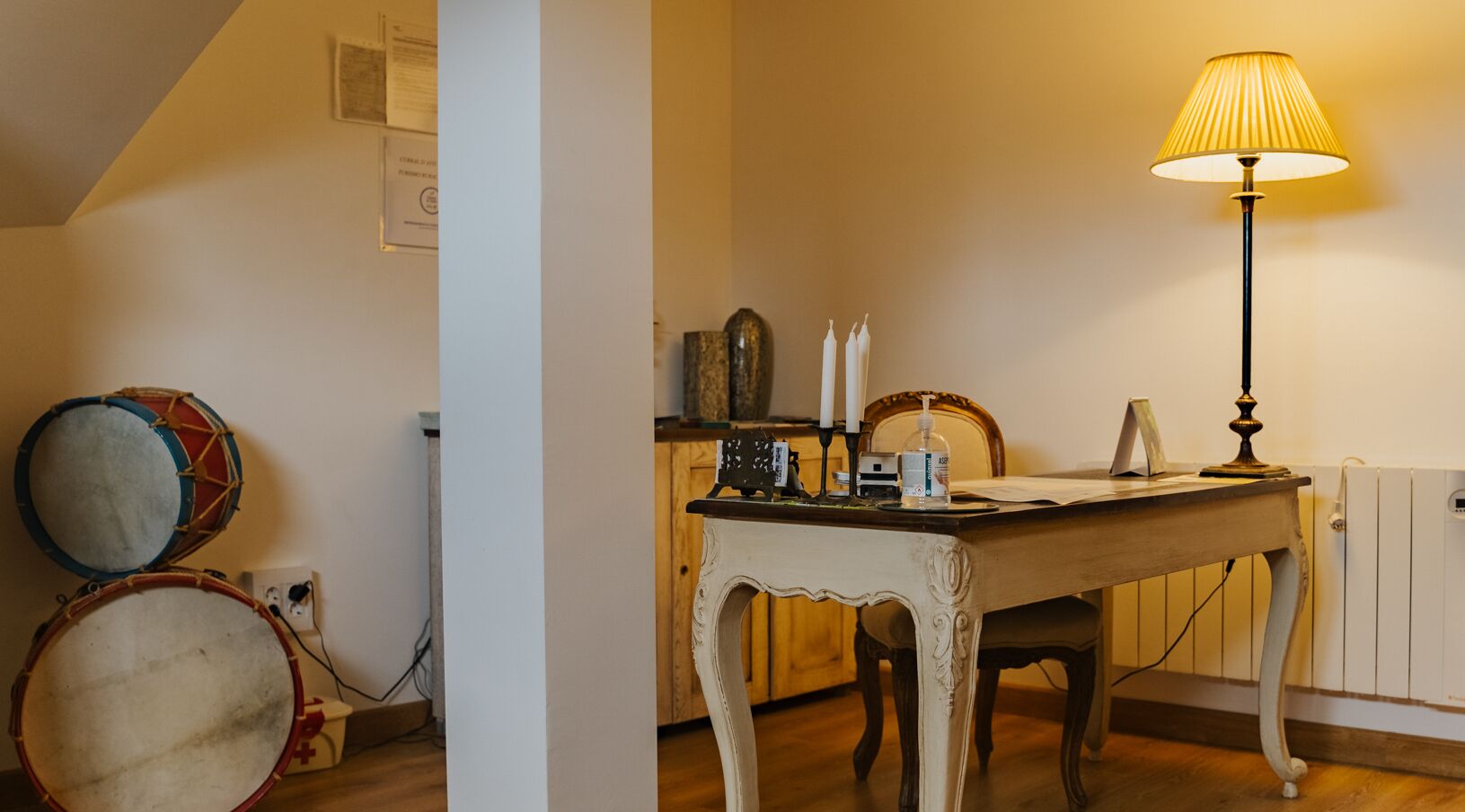 Um quarto com uma mesa de madeira, uma luminária e um conjunto de bateria.