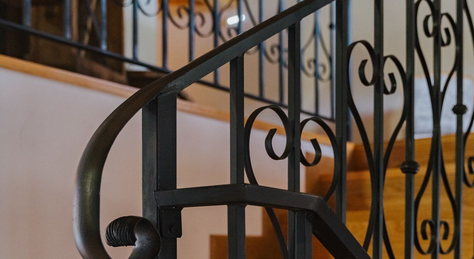 Un gros plan d’une rampe d’escalier en métal, ornée de motifs complexes.
