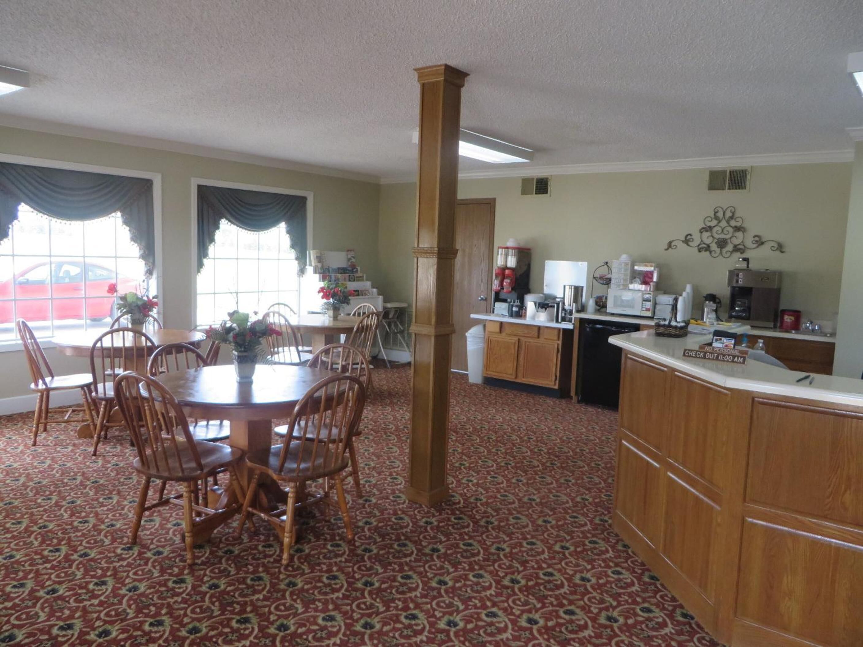 A dining area with a round table and chairs, a kitchen with a counter and appliances, and a patterned carpet.