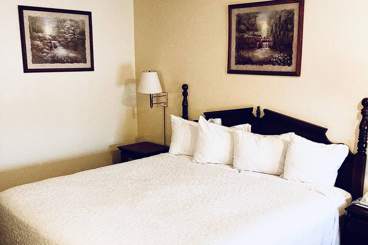 A large bed with white linens, a wooden headboard, and two bedside tables with lamps.