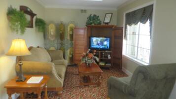 A living room with a sofa, armchair, coffee table, TV, and patterned carpet.