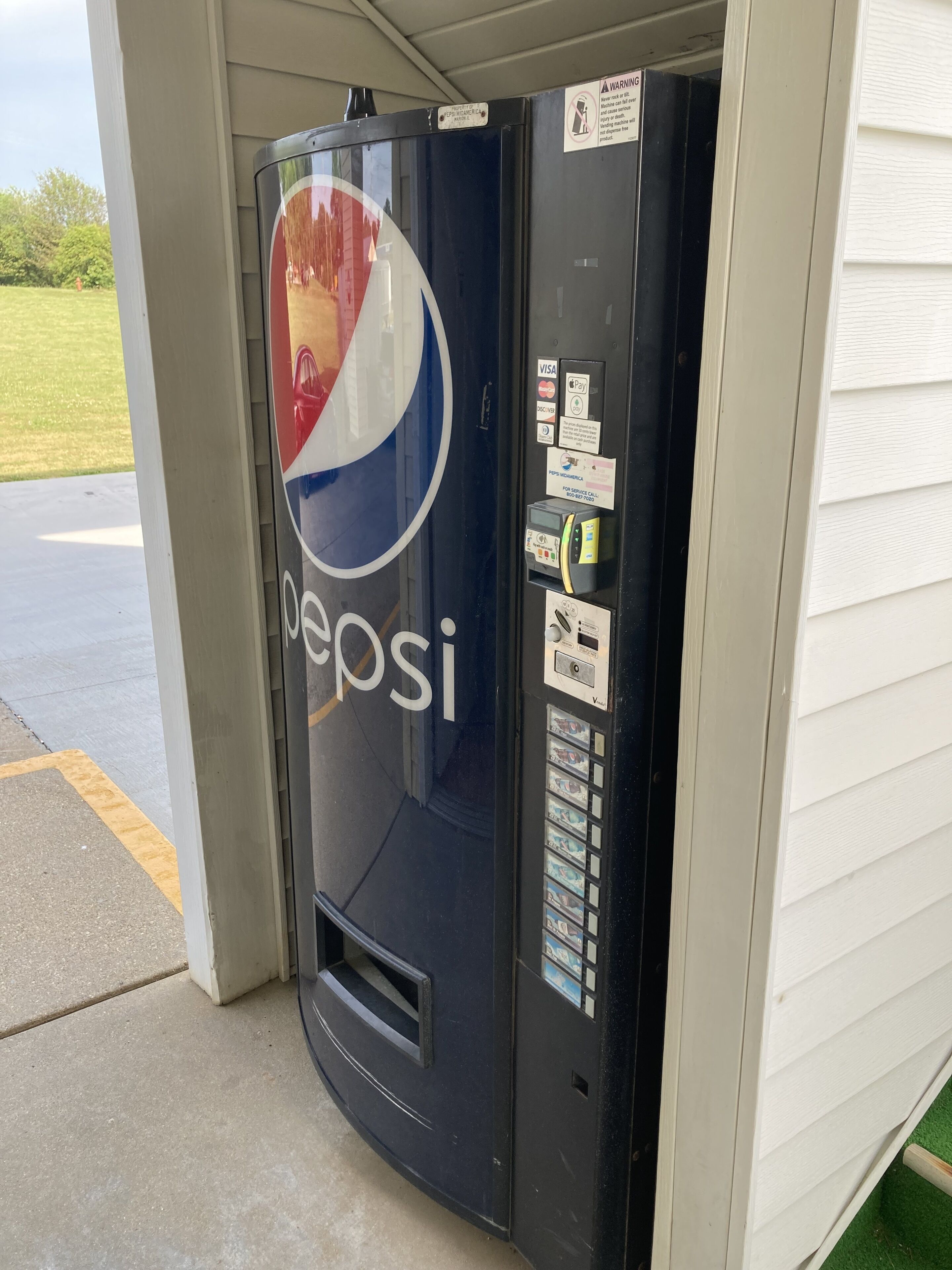 Máquina expendedora de Pepsi con ranura para tarjetas de pago, ranura para monedas y zona de dispensación de bebidas.