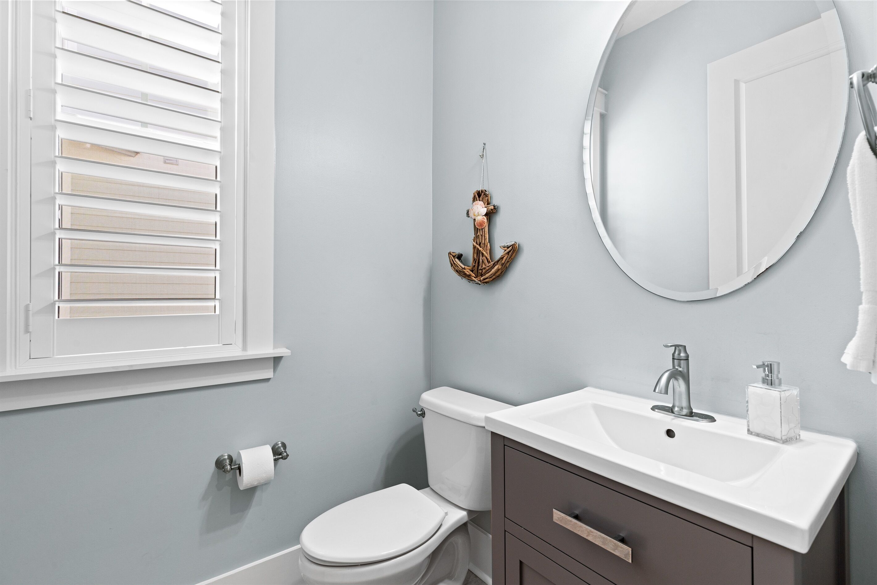 A bathroom with a toilet, sink, and window with blinds.