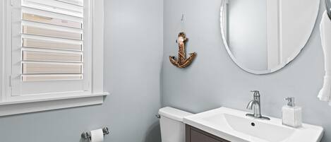 A bathroom with a toilet, sink, and window with blinds.
