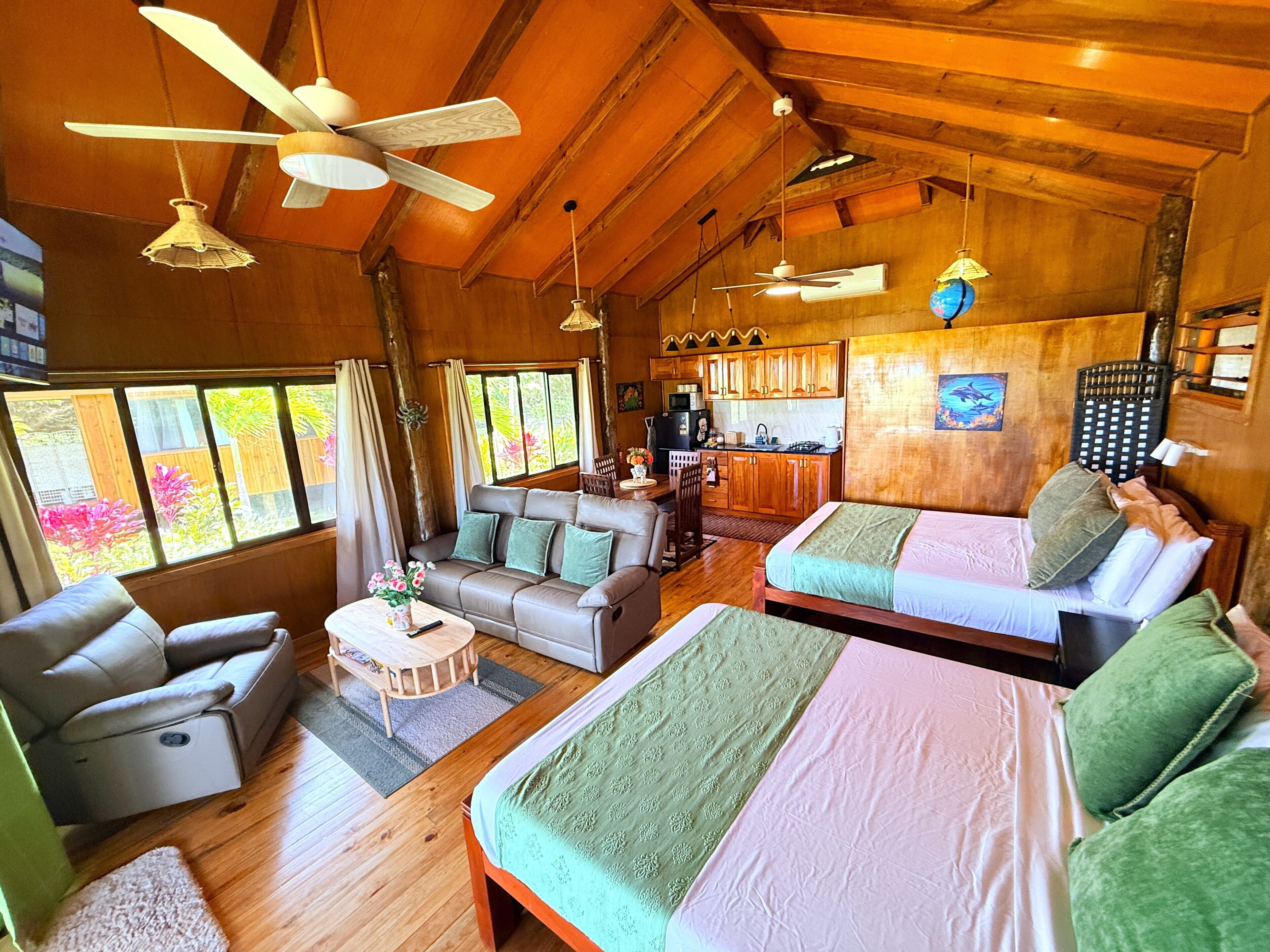 A spacious room with a sofa, a bed, a dining area, and a kitchen.