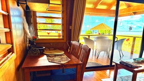 Un coin repas en bois, avec une table, des chaises et une vue sur la terrasse extérieure.
