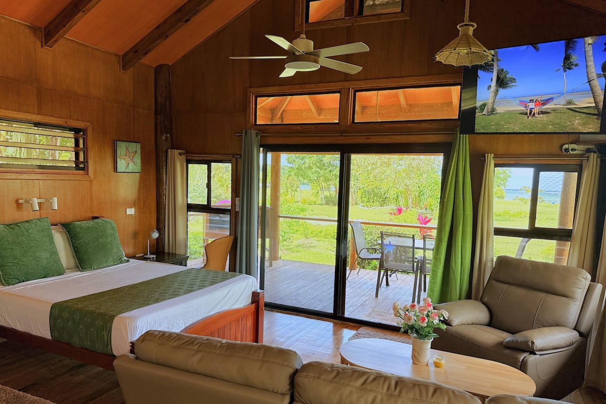 Een kamer met een bed, een bank, een tafel en een balkon met uitzicht op het landschap.