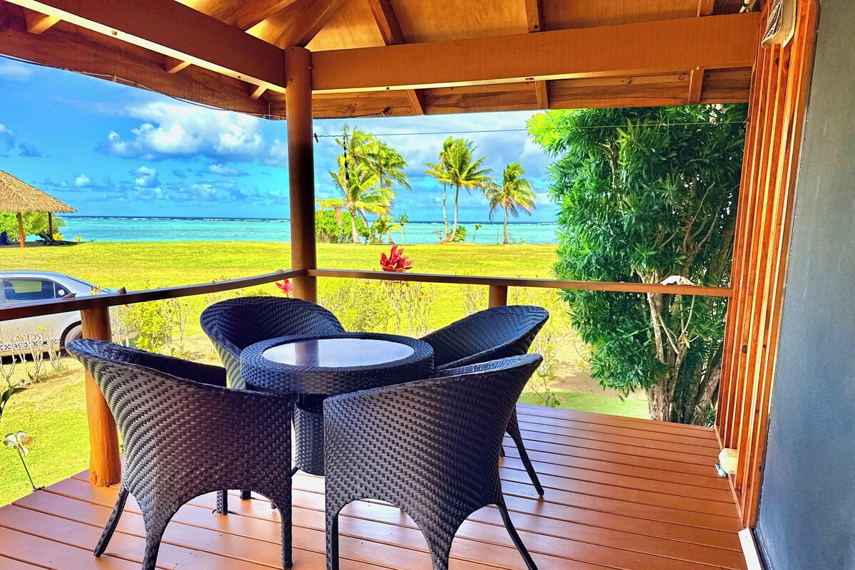 A covered outdoor area with wicker furniture and a view of the ocean.